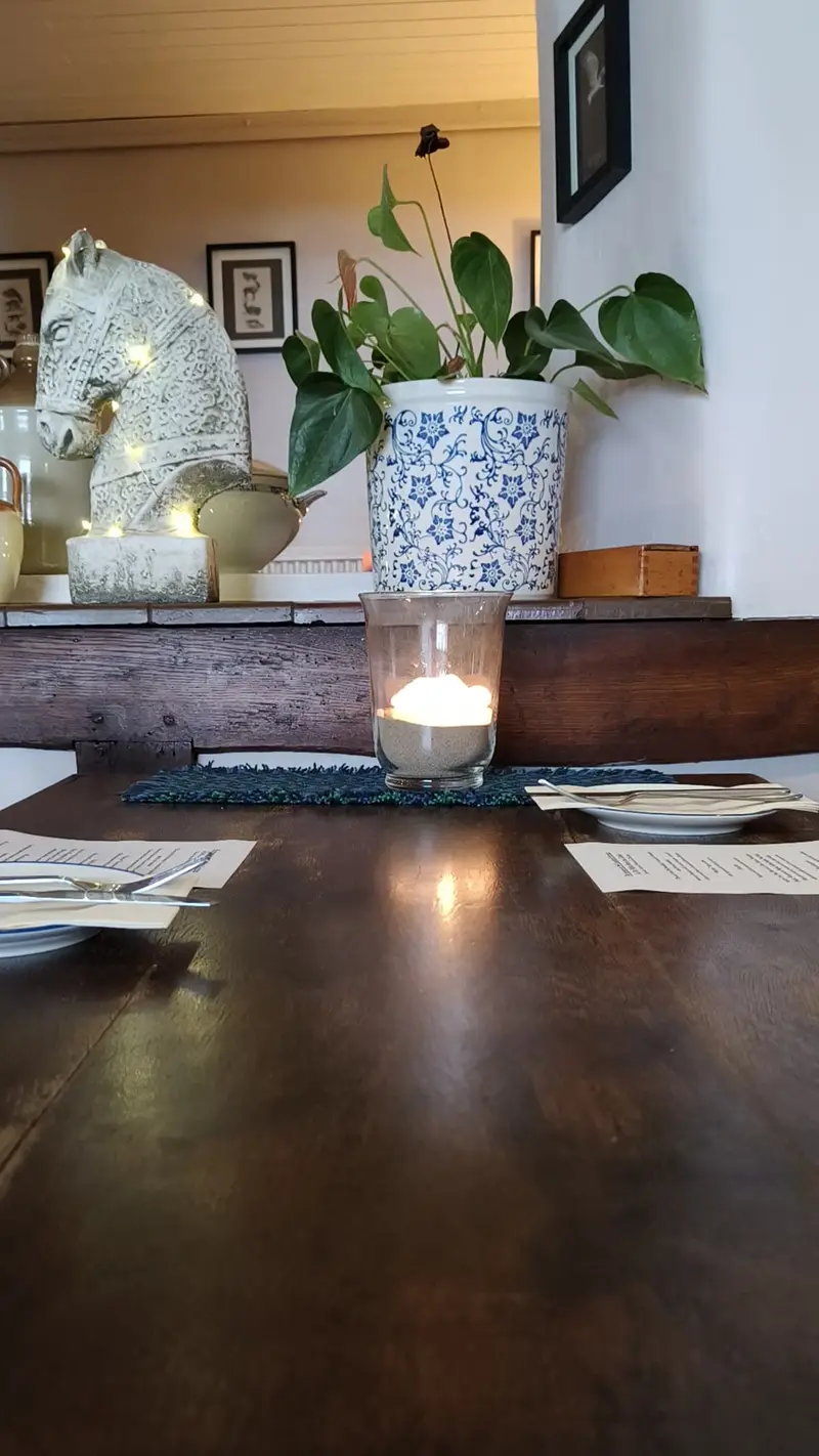 Table with candle and decorative plant in pub interior.