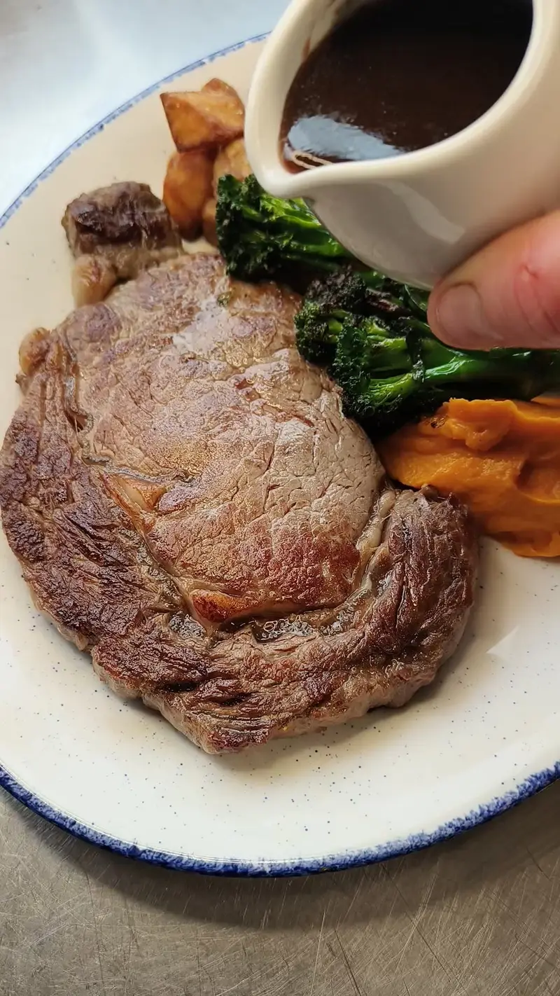 Steak with sauce, broccoli, and sweet potato mash.