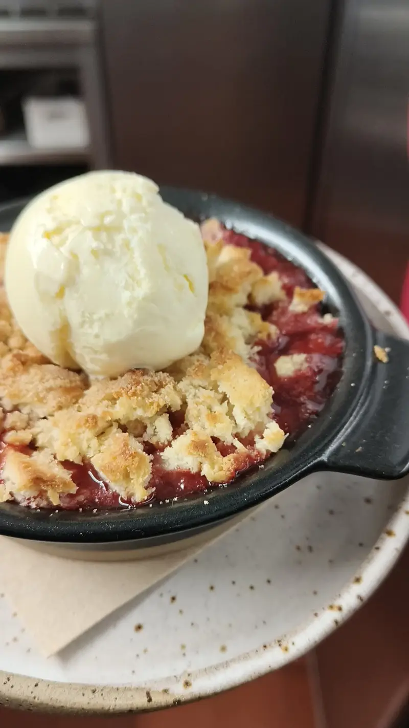 Dessert with ice cream on top in a black dish.